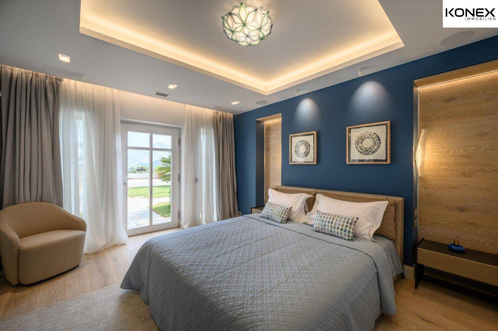 Helles Schlafzimmer mit blauer Akzentwand, Holzboden und Zugang zum Garten.