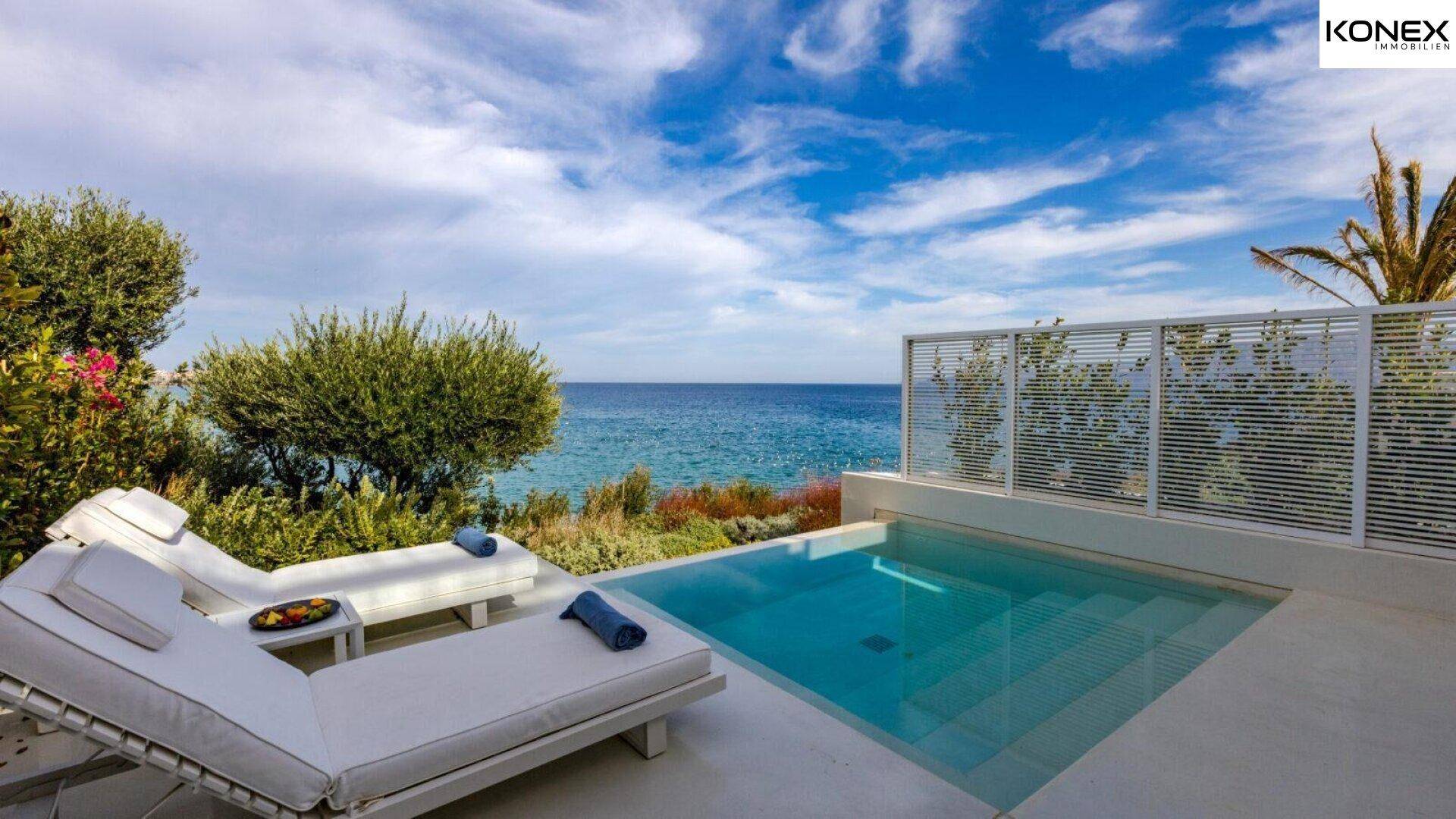 Privater Poolbereich mit bequemen Liegen und weitem Meerblick unter strahlend blauem Himmel.