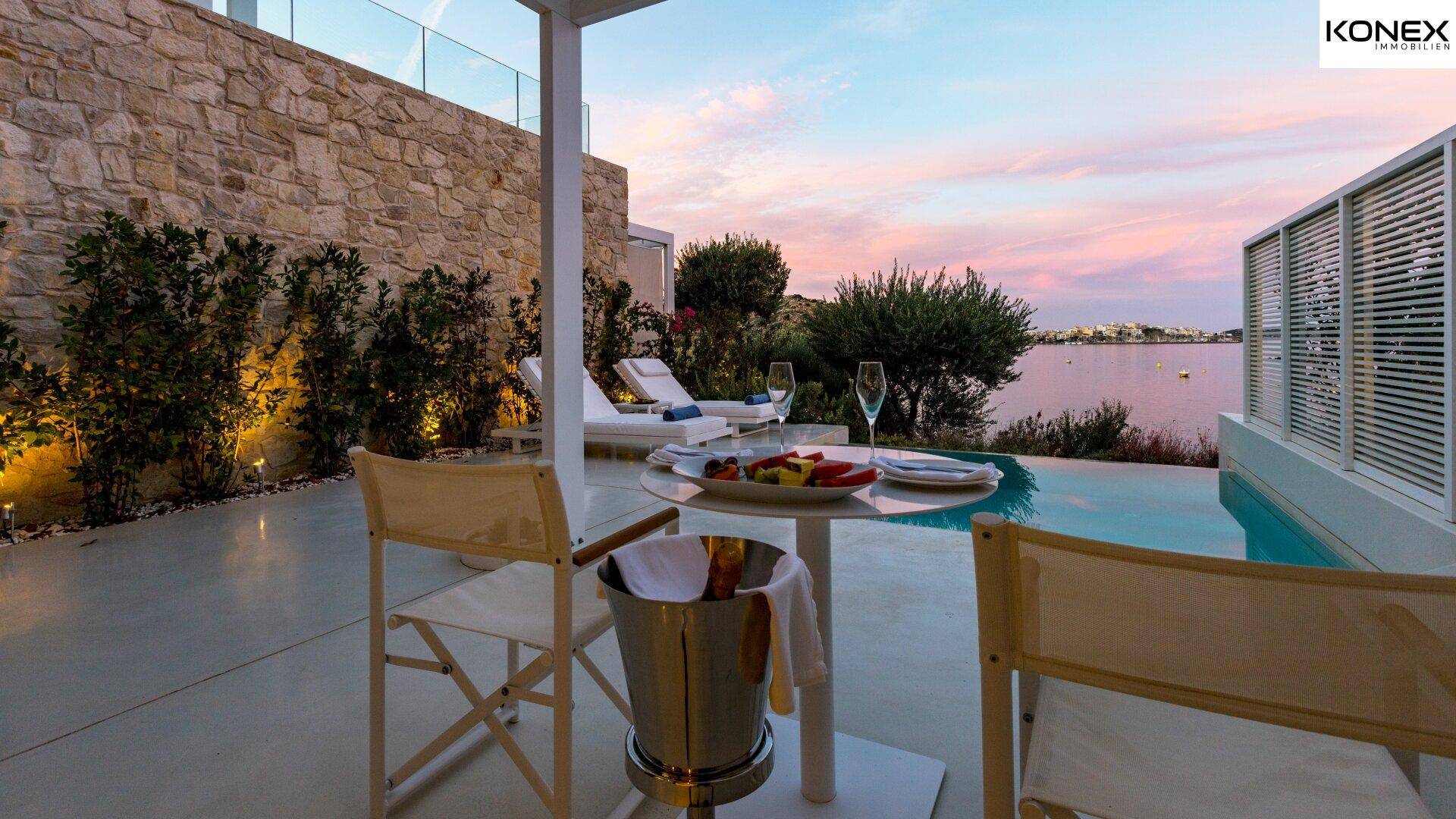 Einladender Essbereich im Freien neben einem privaten Pool mit Meerblick während des Sonnenuntergangs.