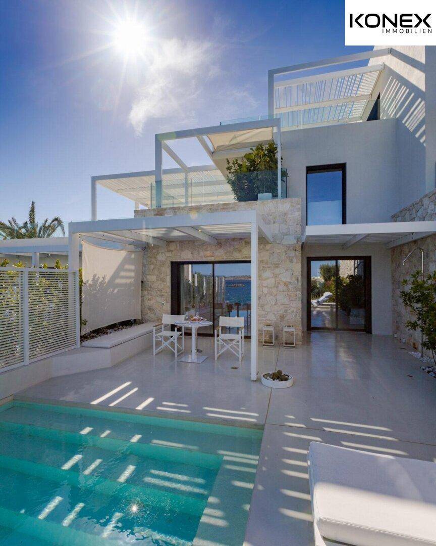 Sonnige private Terrasse mit Pool und moderner Villa, umgeben von mediterraner Vegetation.