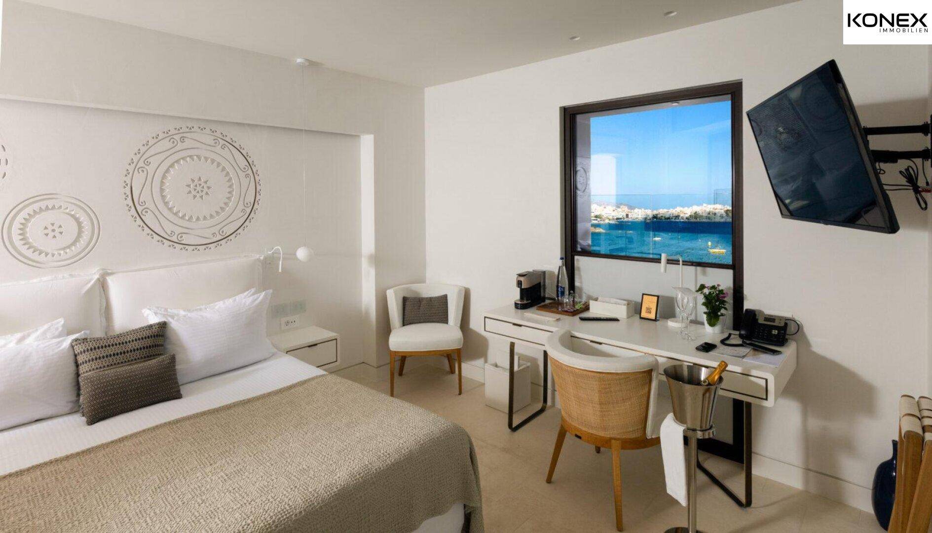 Helles Schlafzimmer mit modernem Design, komfortablem Bett und Schreibtisch mit Meerblick.