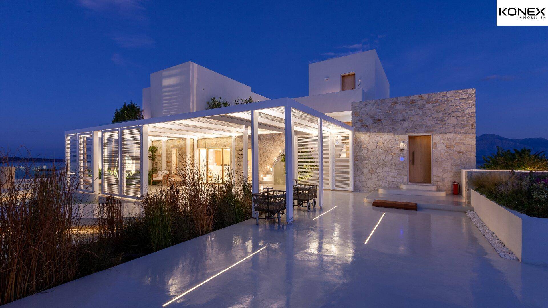 Moderne Villa bei Nacht mit beleuchteten Wegen und stilvoller Außenbeleuchtung.