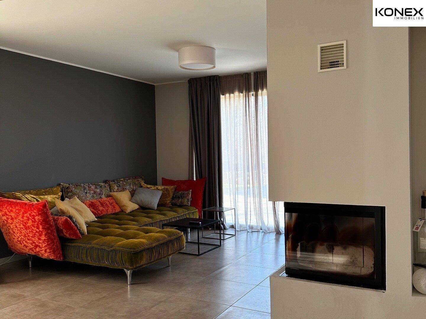 Helles Wohnzimmer mit modernem Kamin, bequemer Couch und Zugang zum Außenbereich.