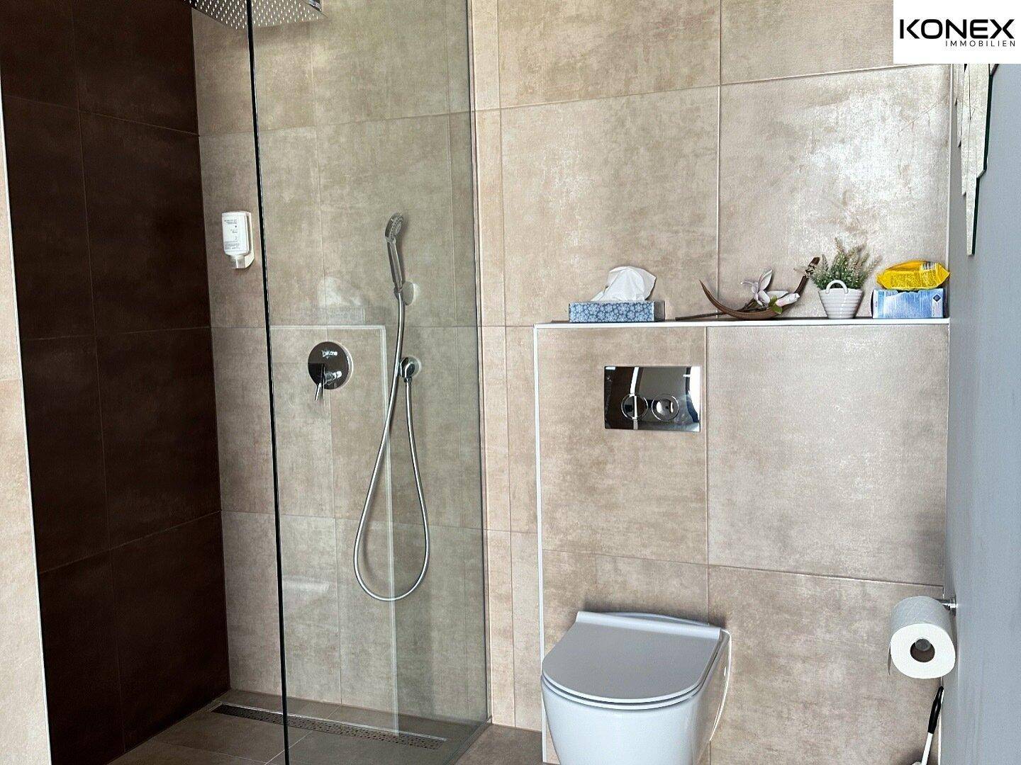 Modernes Badezimmer mit ebenerdiger Dusche, Wand-WC und großformatigen Fliesen.