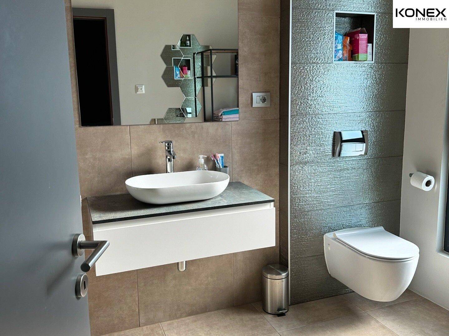 Helles Badezimmer mit modernem Waschbecken, Wand-WC und großem Spiegel.
