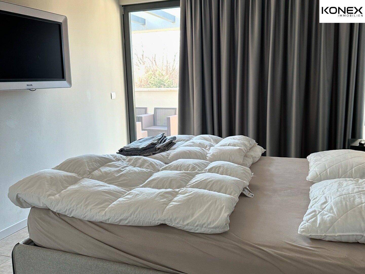 Helles Schlafzimmer mit großem Bett und direktem Zugang zu einer Außenterrasse.
