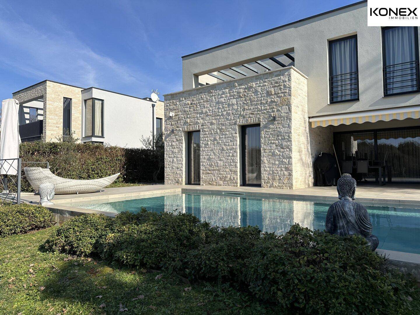 Moderne Villa mit Swimmingpool, Steinfassade und gepflegtem Gartenbereich.