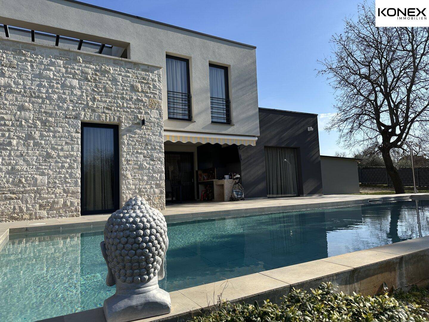 Weitläufige Außenansicht der modernen Villa mit Swimmingpool und umliegender Natur.