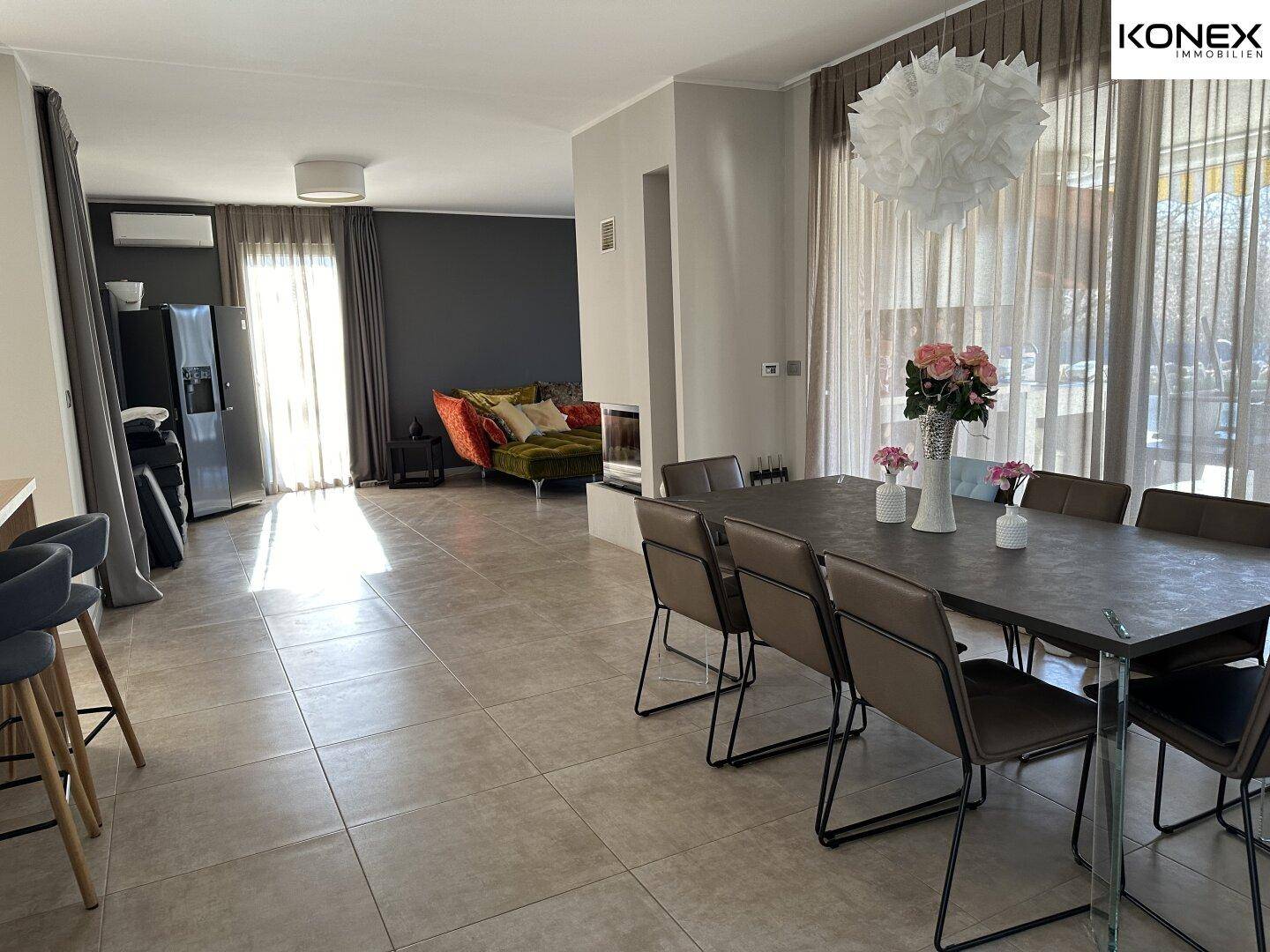 Geräumiger Wohn- und Essbereich mit großem Esstisch, Fliesenboden und Zugang zur Terrasse.