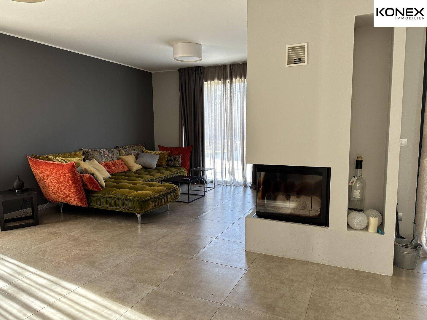 Helles Wohnzimmer mit modernem Kamin, bequemer Couch und Zugang zum Außenbereich.