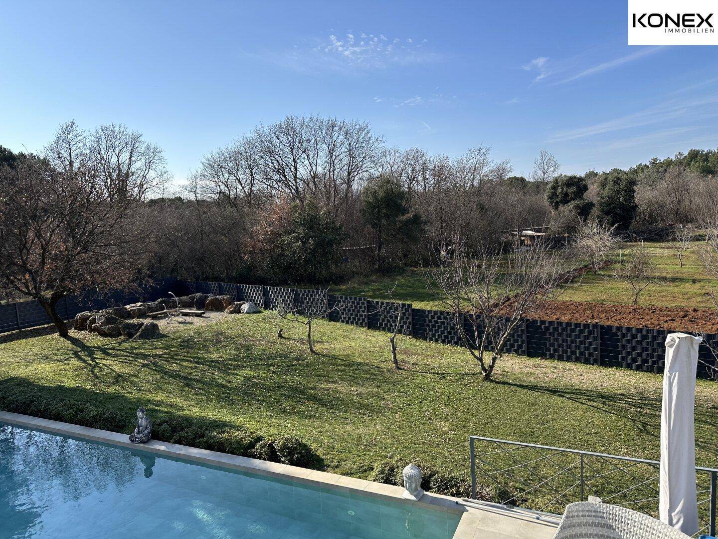 Weitläufiger Garten mit Pool, Rasenflächen und Blick auf die umliegende Landschaft.