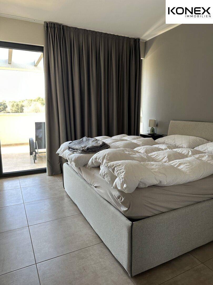 Helles Schlafzimmer mit großem Bett und direktem Zugang zu einer Außenterrasse.