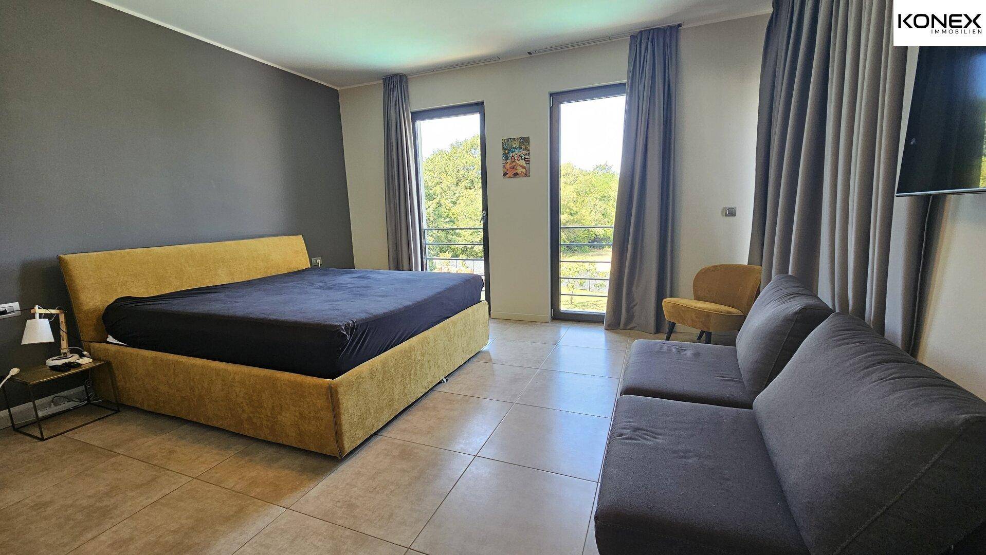 Helles Schlafzimmer mit großem Bett, bequemen Sesseln und viel Tageslicht.