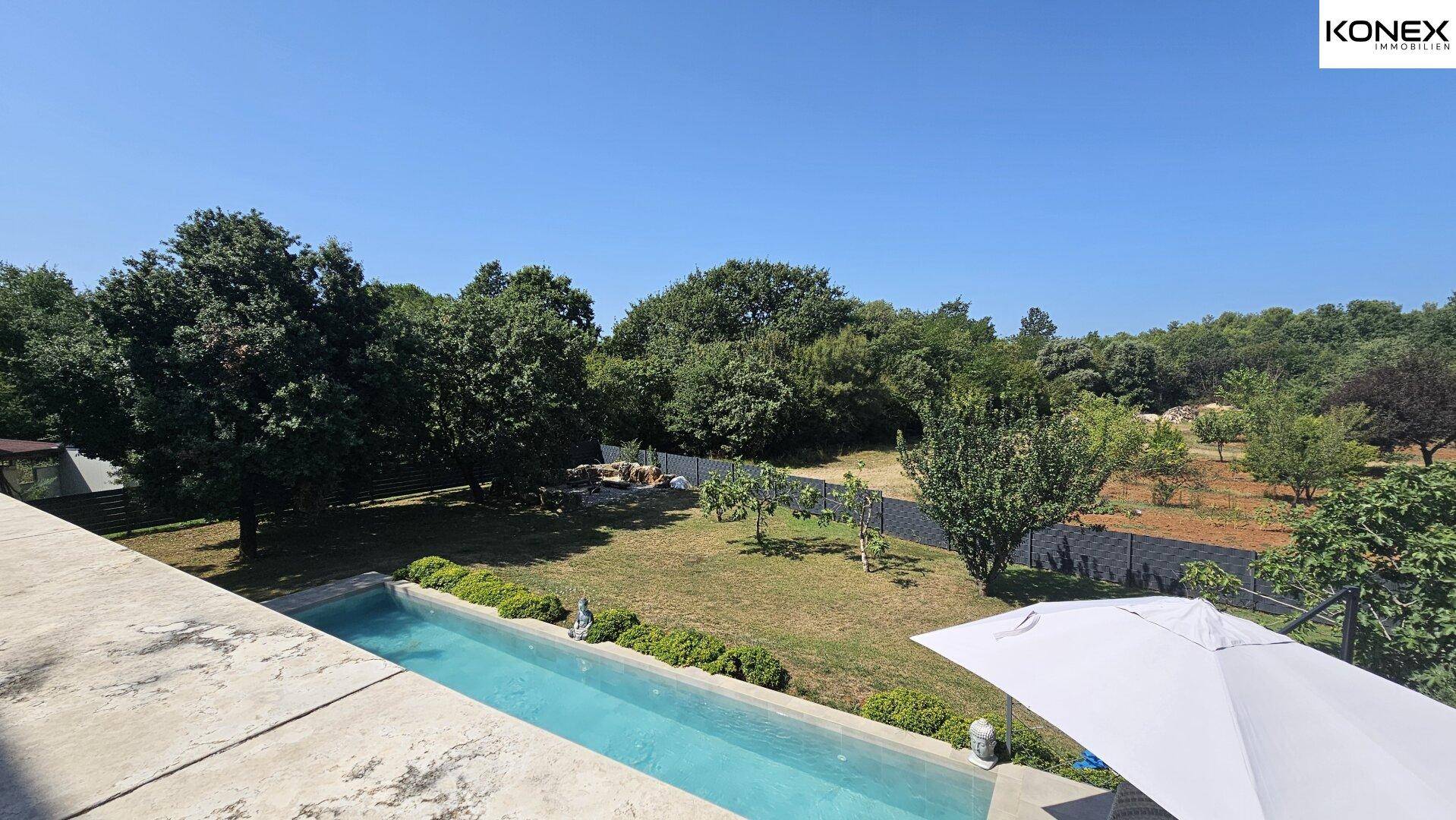 Weitläufiger Garten mit Pool, Rasenflächen und Blick auf die umliegende Landschaft.