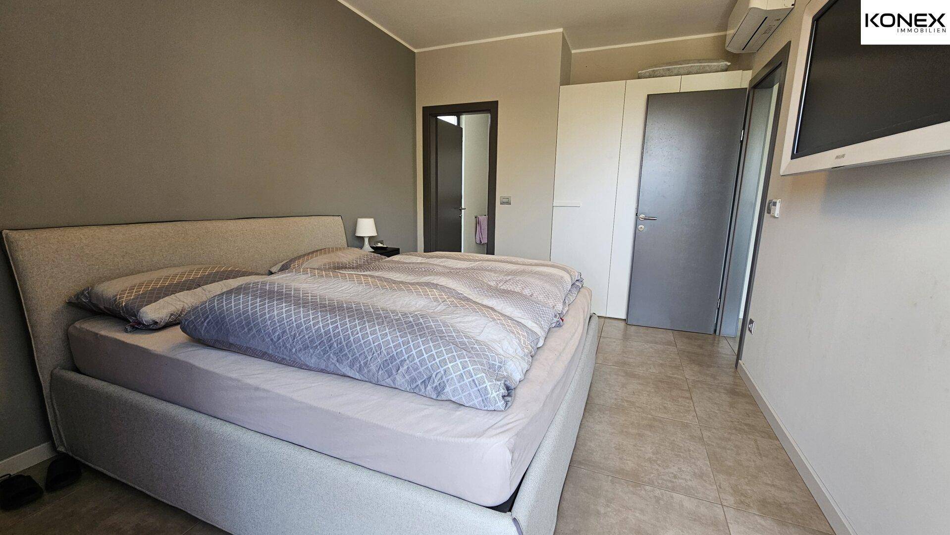 Schlafzimmer mit großem Bett, Einbauschränken und Klimaanlage für angenehme Temperaturen.