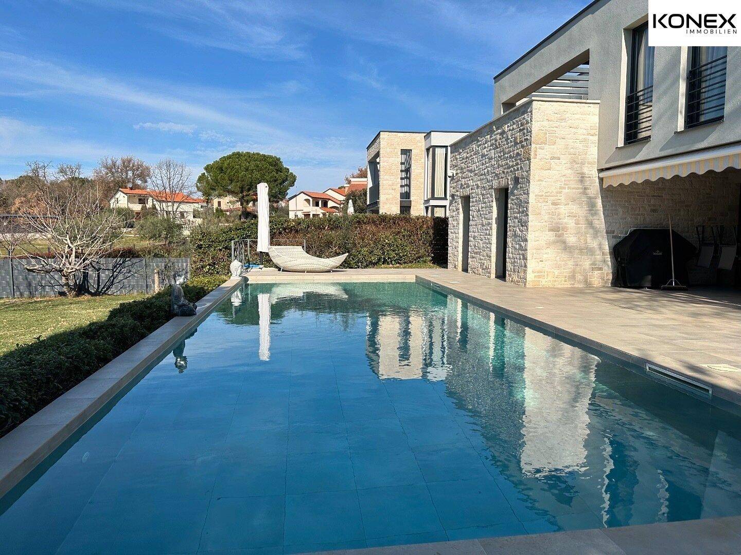 Panoramablick auf die moderne Villa mit großem Pool und gepflegtem Gartenbereich.