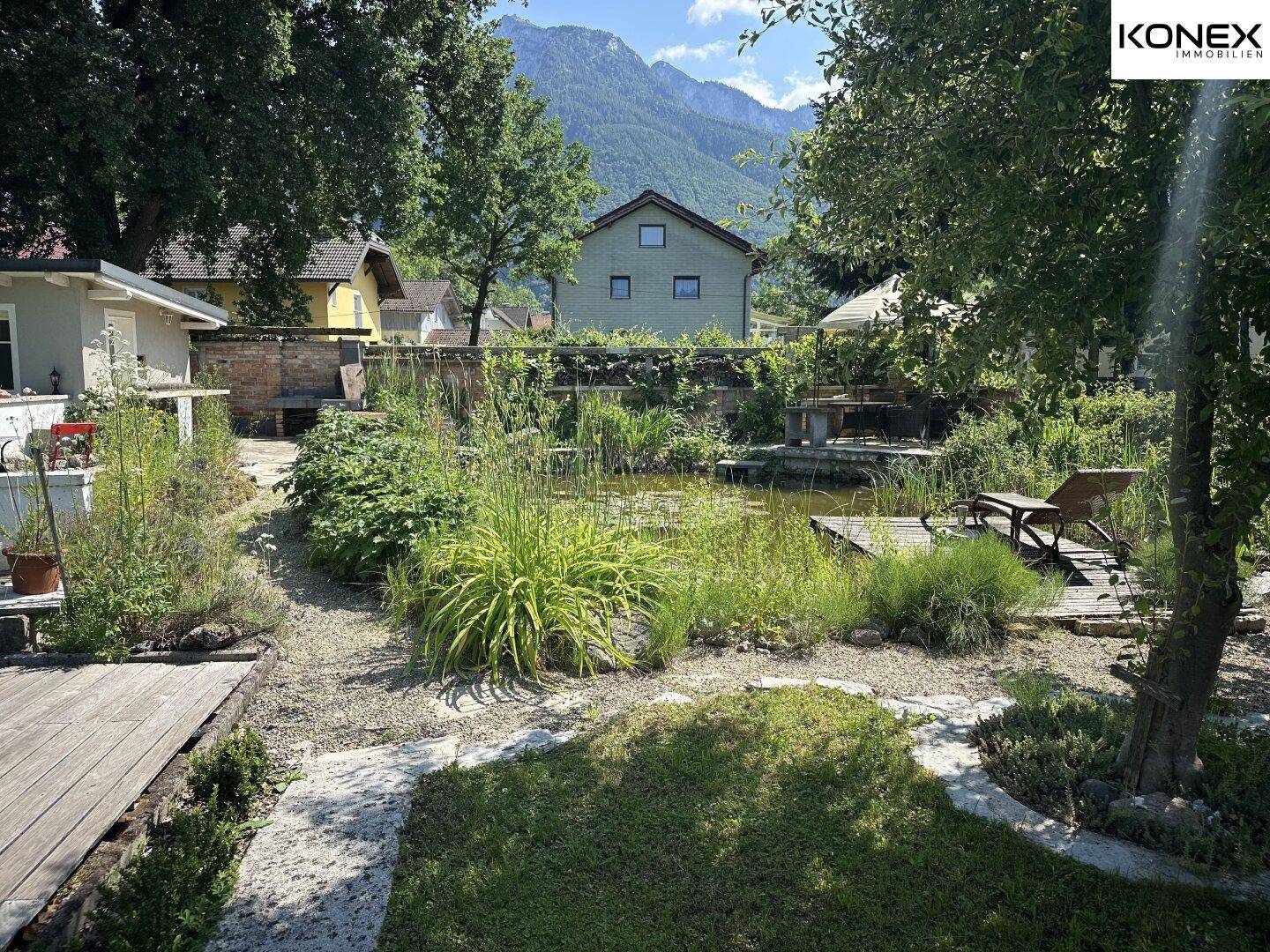 Großzügiger Garten mit Teich, Liegewiese und beeindruckendem Bergblick im Hintergrund.