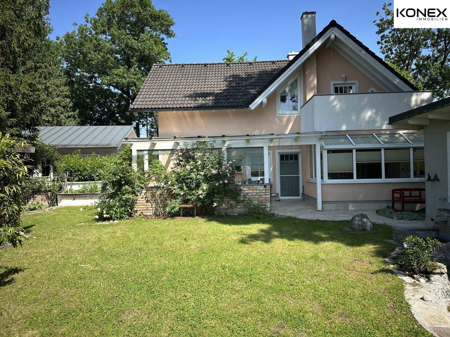 Rückseite des Hauses mit gepflegtem Rasen und einer überdachten Terrasse.