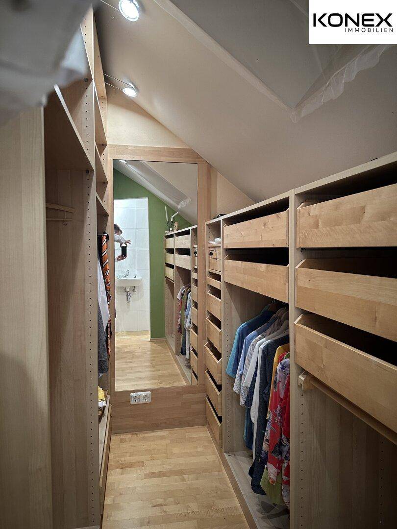 Geräumiger begehbarer Kleiderschrank mit Spiegel und vielen Ablagemöglichkeiten.