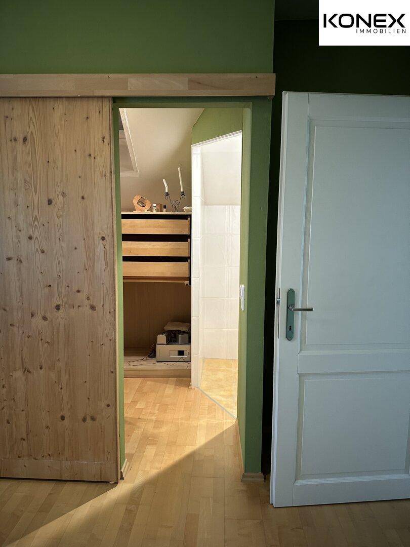 Schlafzimmer mit Schiebetür, die zu einem begehbaren Kleiderschrank führt.