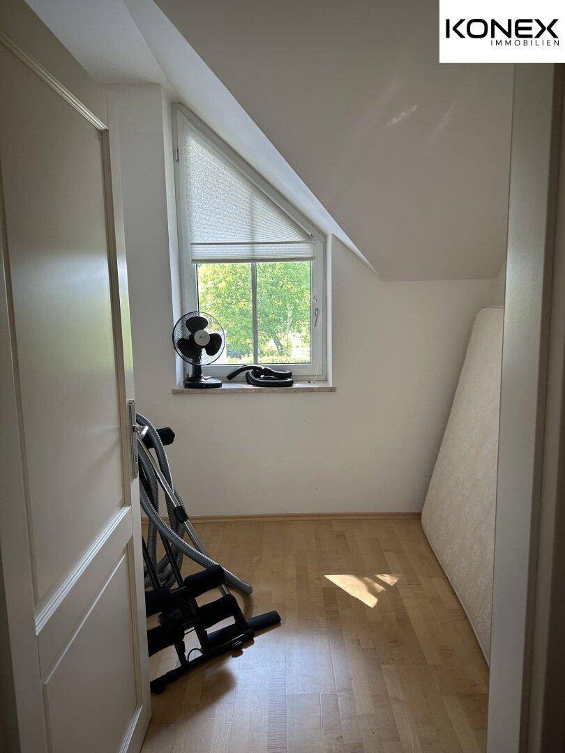Kleiner Raum mit Dachschräge und Fenster, genutzt für Sportgeräte oder Abstellfläche.