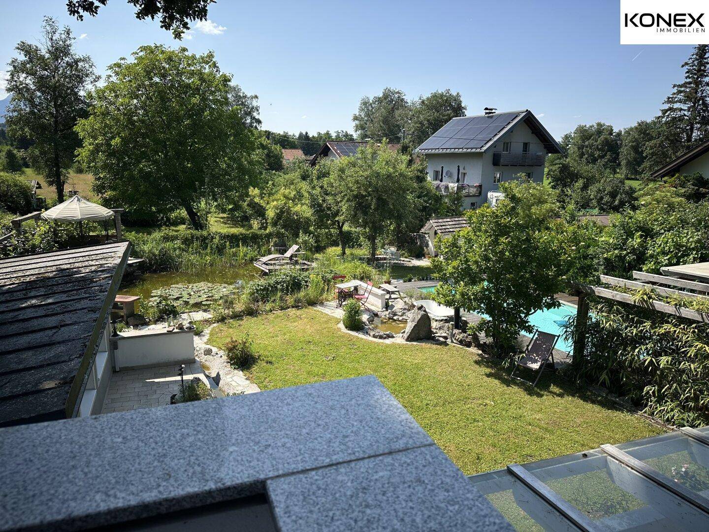 Weitläufiger Gartenbereich mit Swimmingpool, Teich und viel Grün.