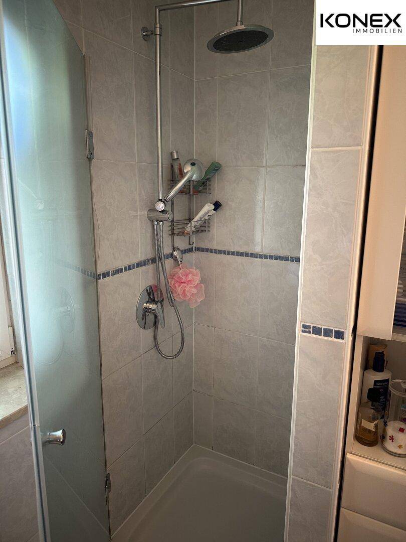 Duschbereich mit modernen grauen Fliesen und Regendusche.