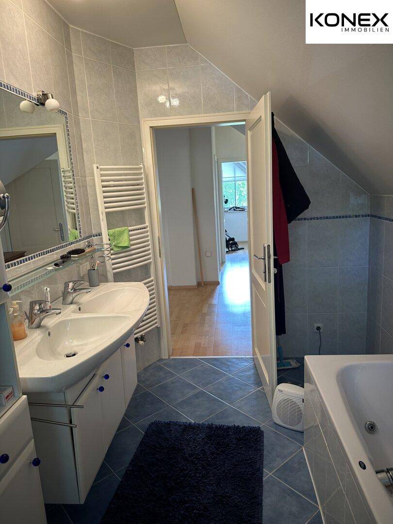 Badezimmer mit Doppelwaschbecken, Badewanne und beheiztem Handtuchhalter.