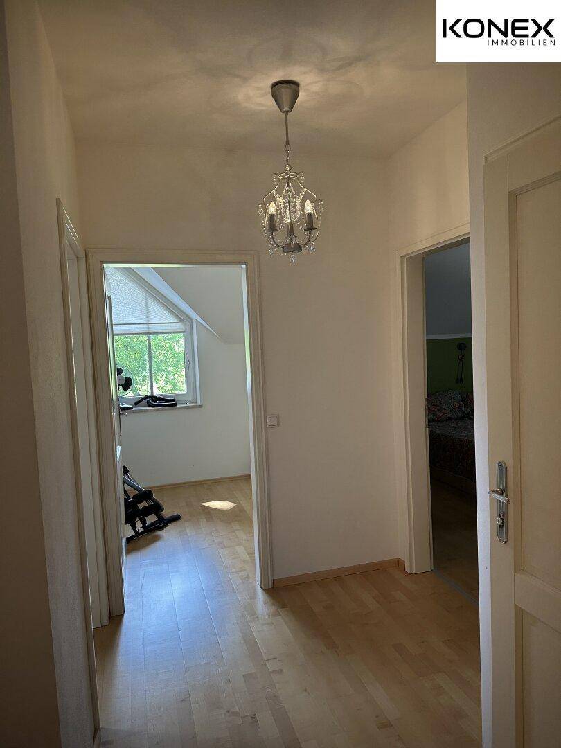 Flur im Obergeschoss mit Holzboden und Kronleuchter, der zu den Zimmern führt.