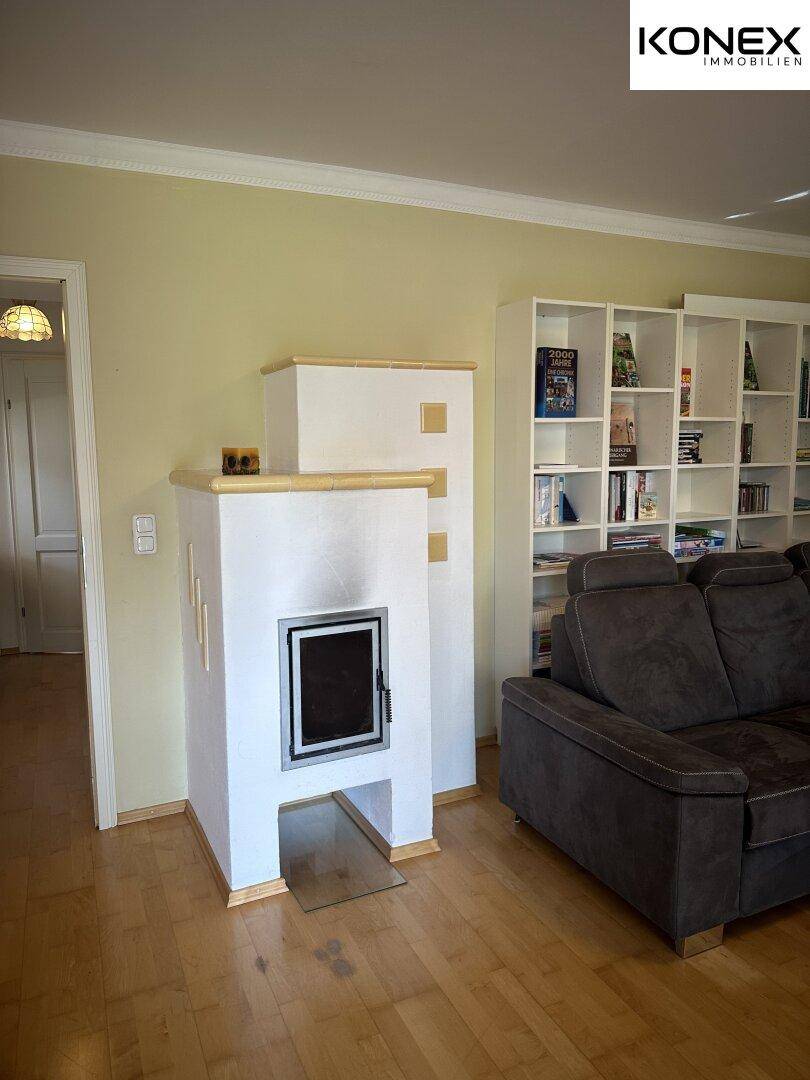Gemütliches Wohnzimmer mit Kachelofen, Sofa und Bücherregal.