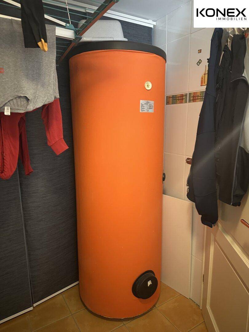Hauswirtschaftsraum mit großem Warmwasserspeicher und Fliesenboden.