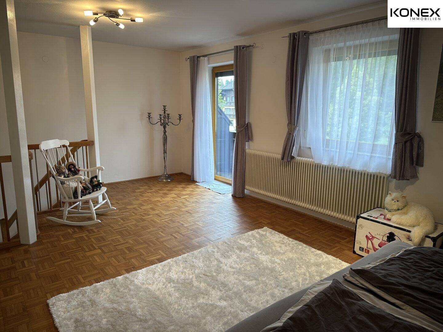 Helles Schlafzimmer mit Parkettboden, Zugang zum Balkon und viel Tageslicht.