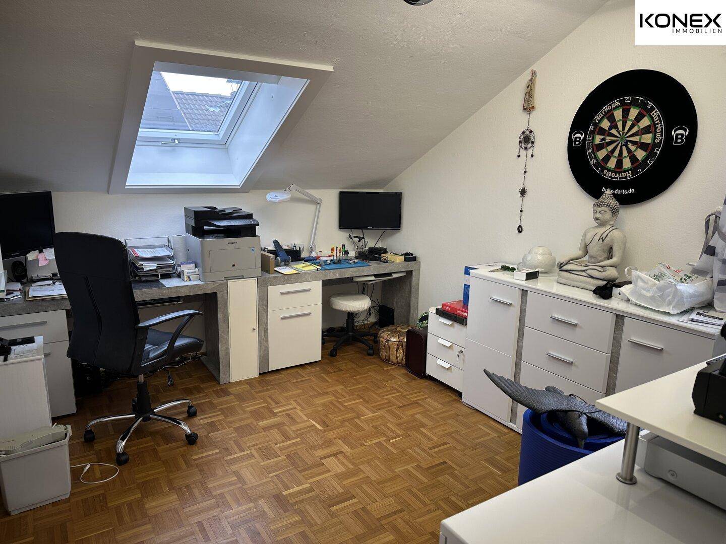 Arbeitszimmer im Dachgeschoss mit Schreibtisch, Büromöbeln und Dachfenster.