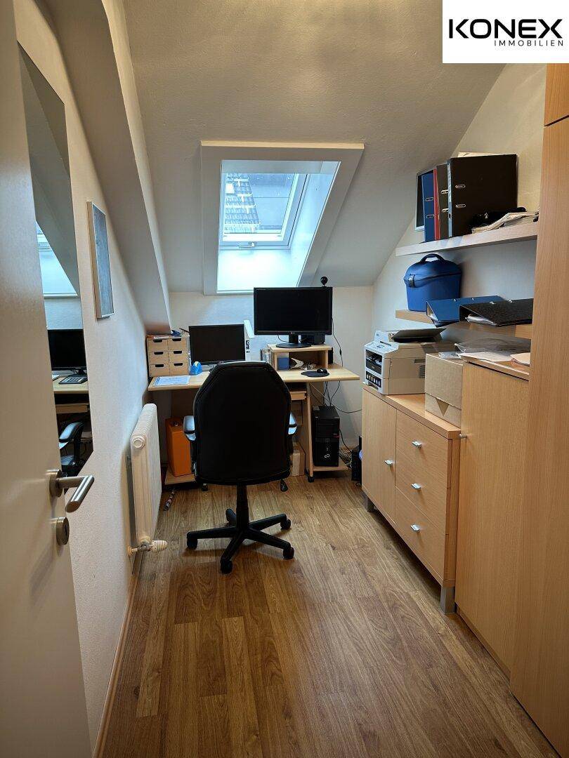Funktionales Arbeitszimmer mit Holzschreibtisch, Regalen und Dachfenster für natürliches Licht.