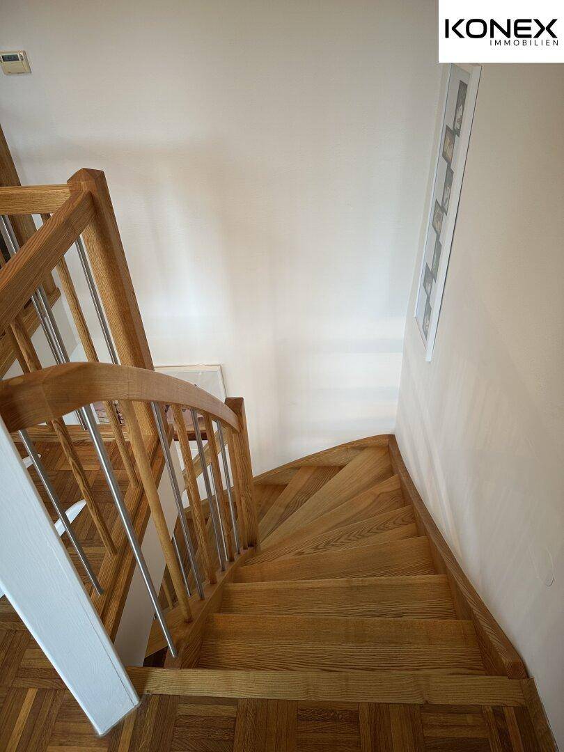 Holztreppe mit Metallgeländer, die die verschiedenen Ebenen des Hauses verbindet.