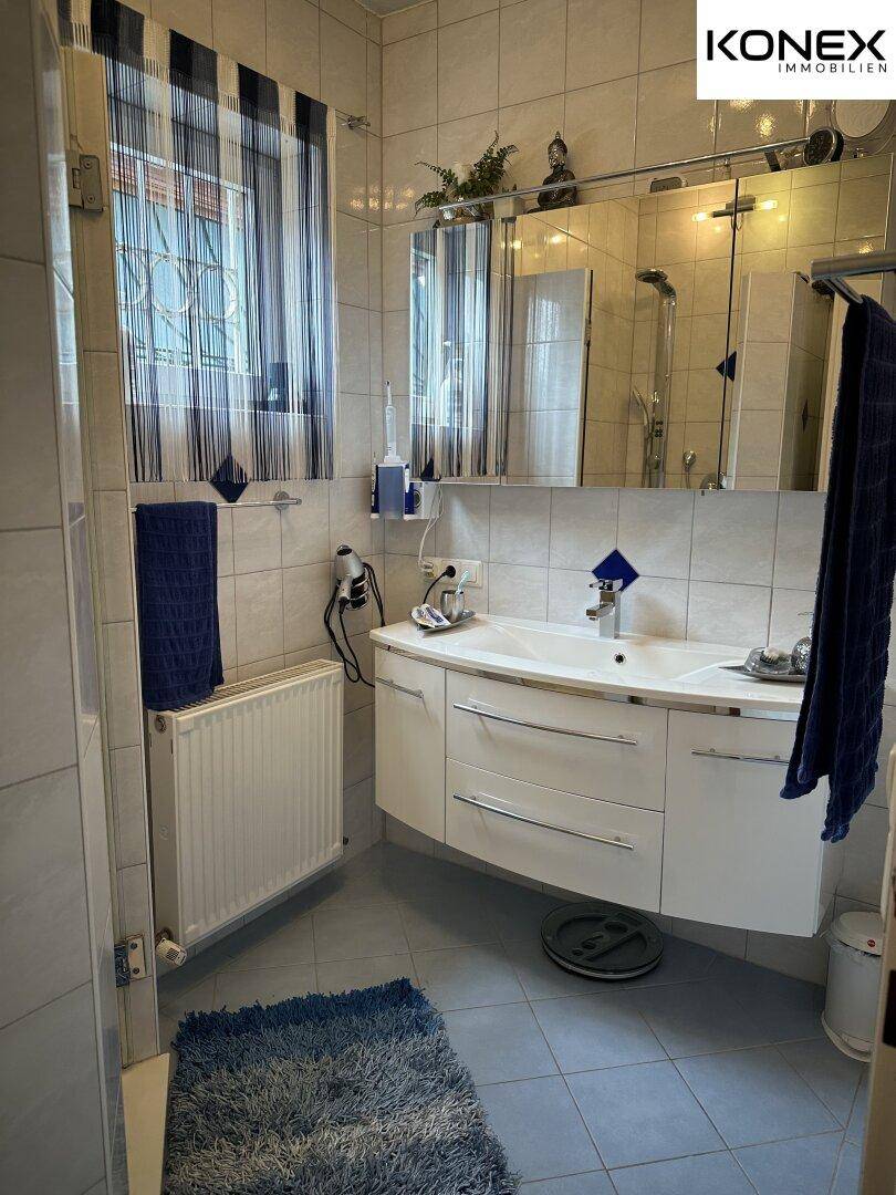 Modernes Badezimmer mit Duschkabine, Waschbecken und beheiztem Handtuchhalter.