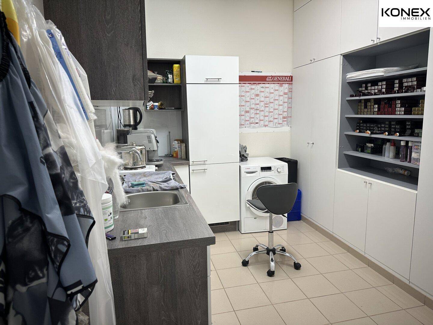 Praktischer Hauswirtschaftsraum mit Waschmaschine, Spülbecken und viel Stauraum.
