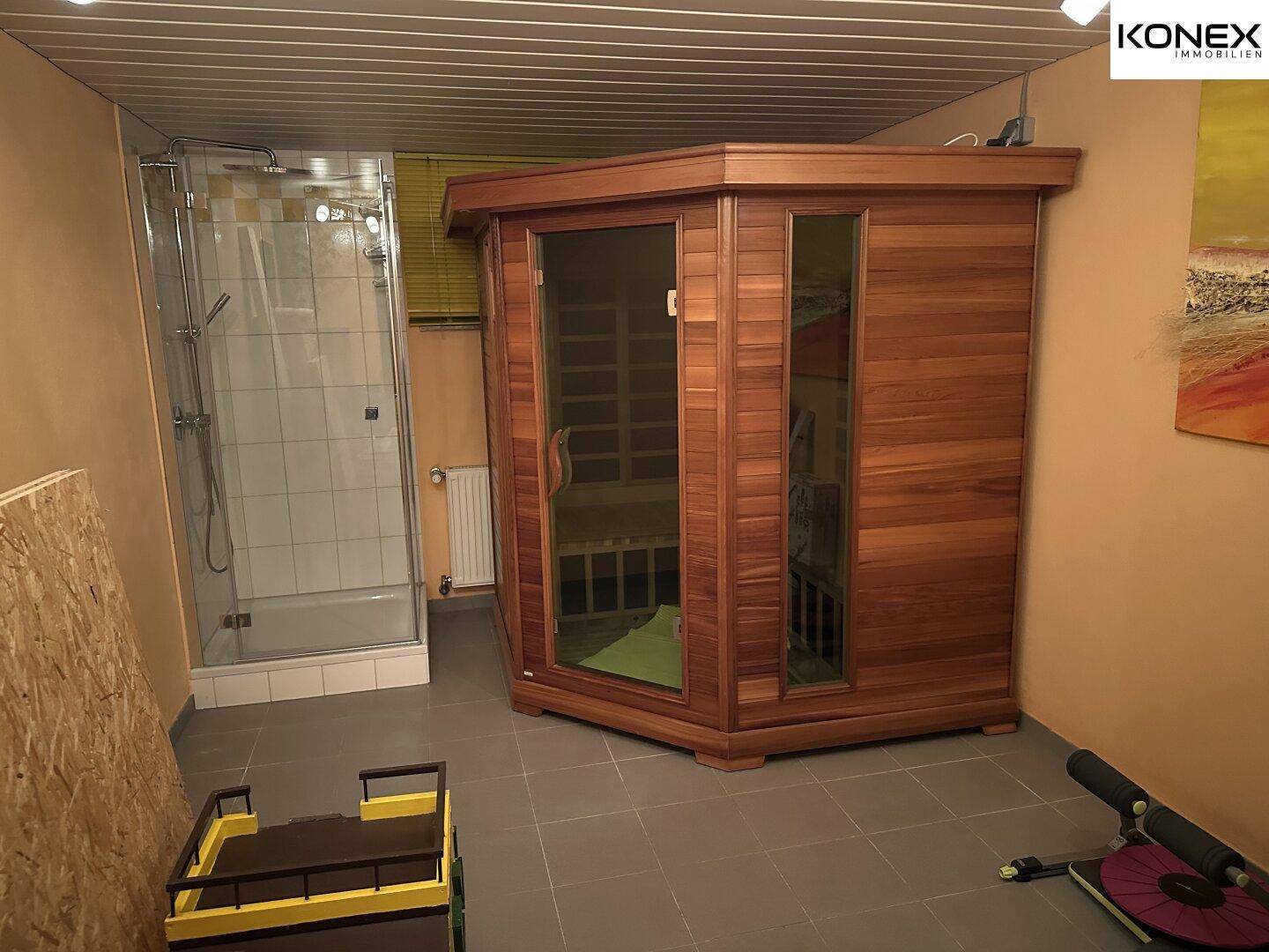 Kleiner Wellnessbereich mit Holzsauna und angrenzender Duschkabine.