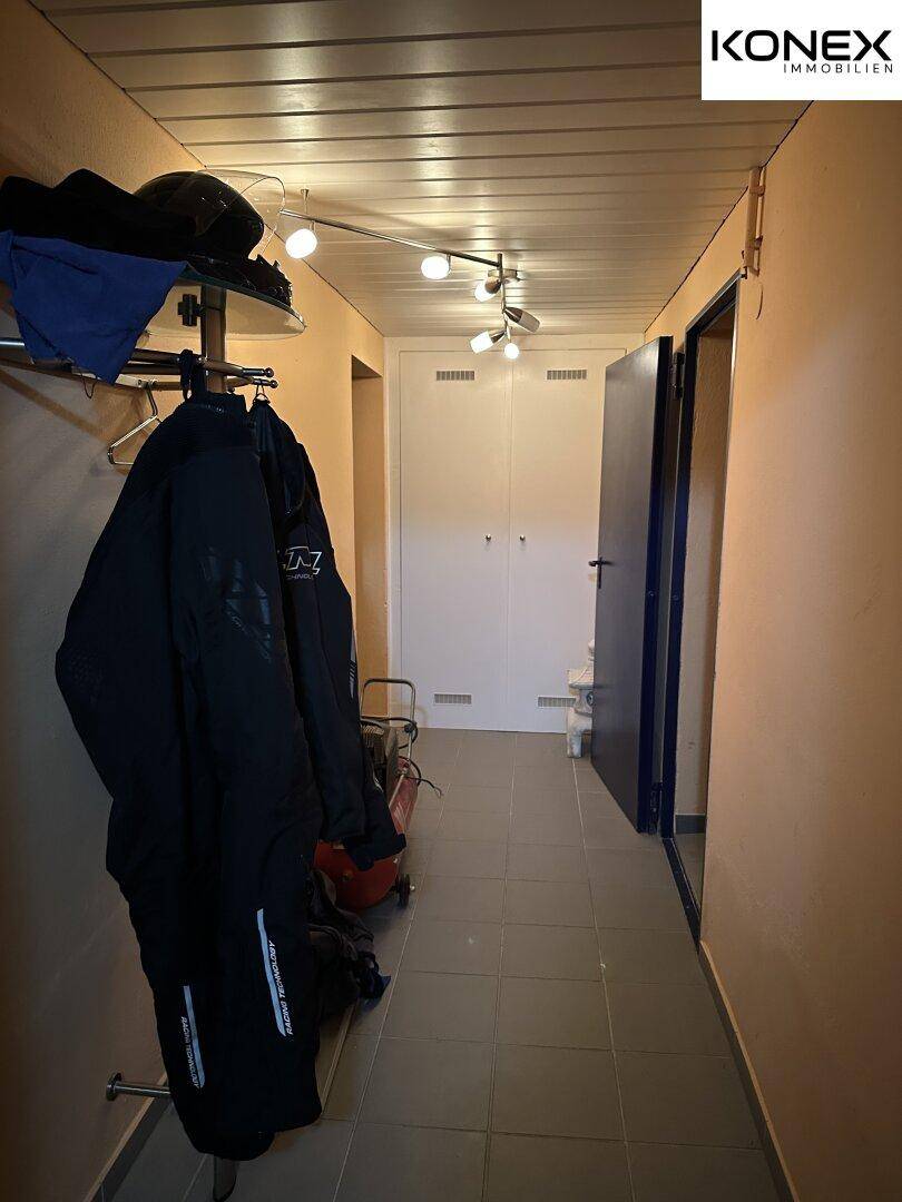 Langer Flur mit Fliesenboden, Garderobe und Zugang zu weiteren Räumen.