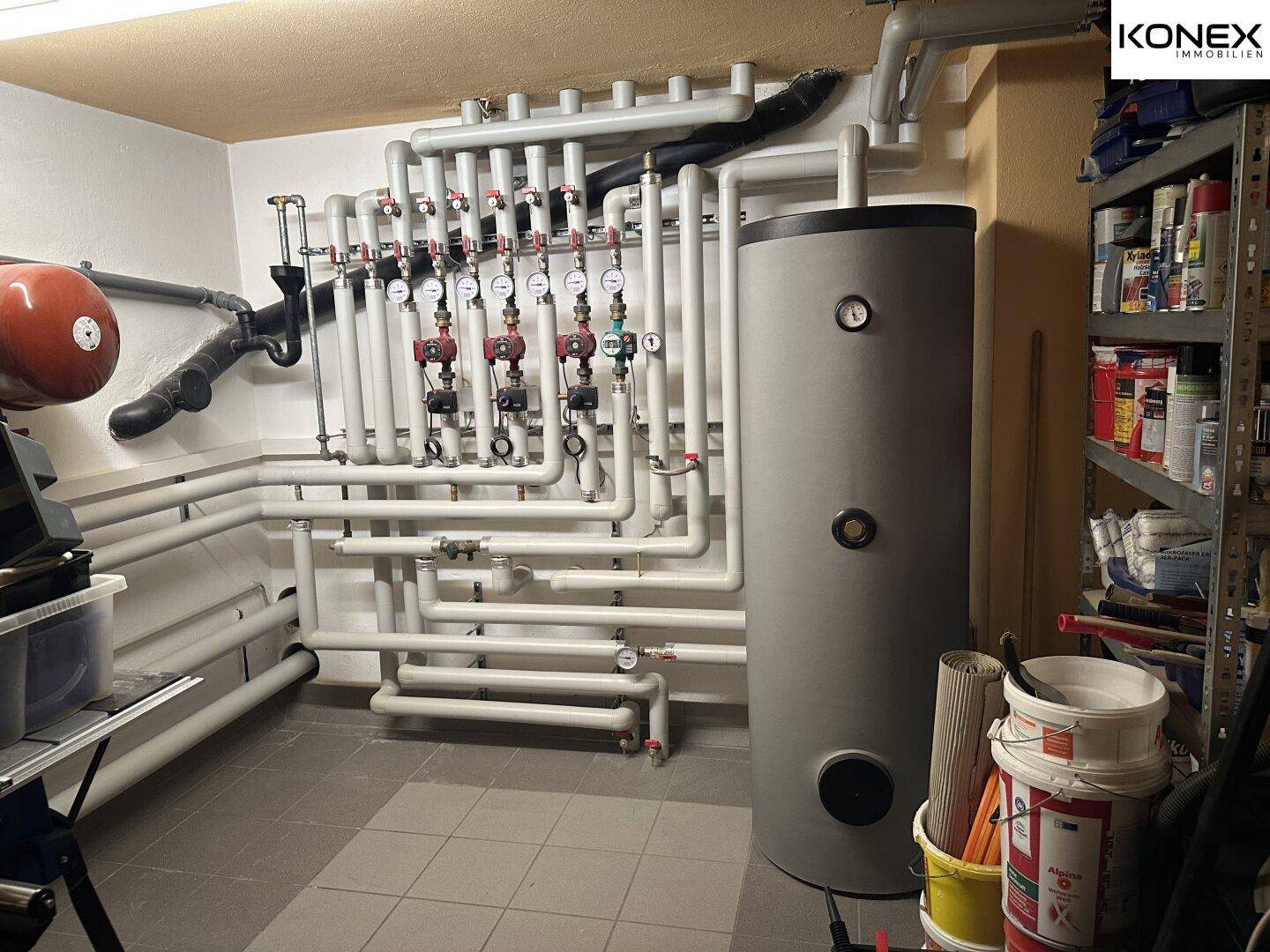 Heizungsraum mit komplexem Rohrsystem und großem Warmwasserspeicher.