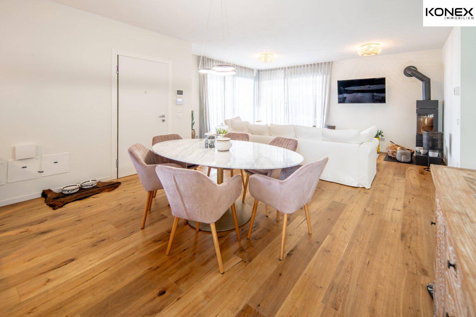 Geräumiger Wohn-Essbereich mit Holzboden, Kaminofen und großem Esstisch, ideal für gesellige Abende.