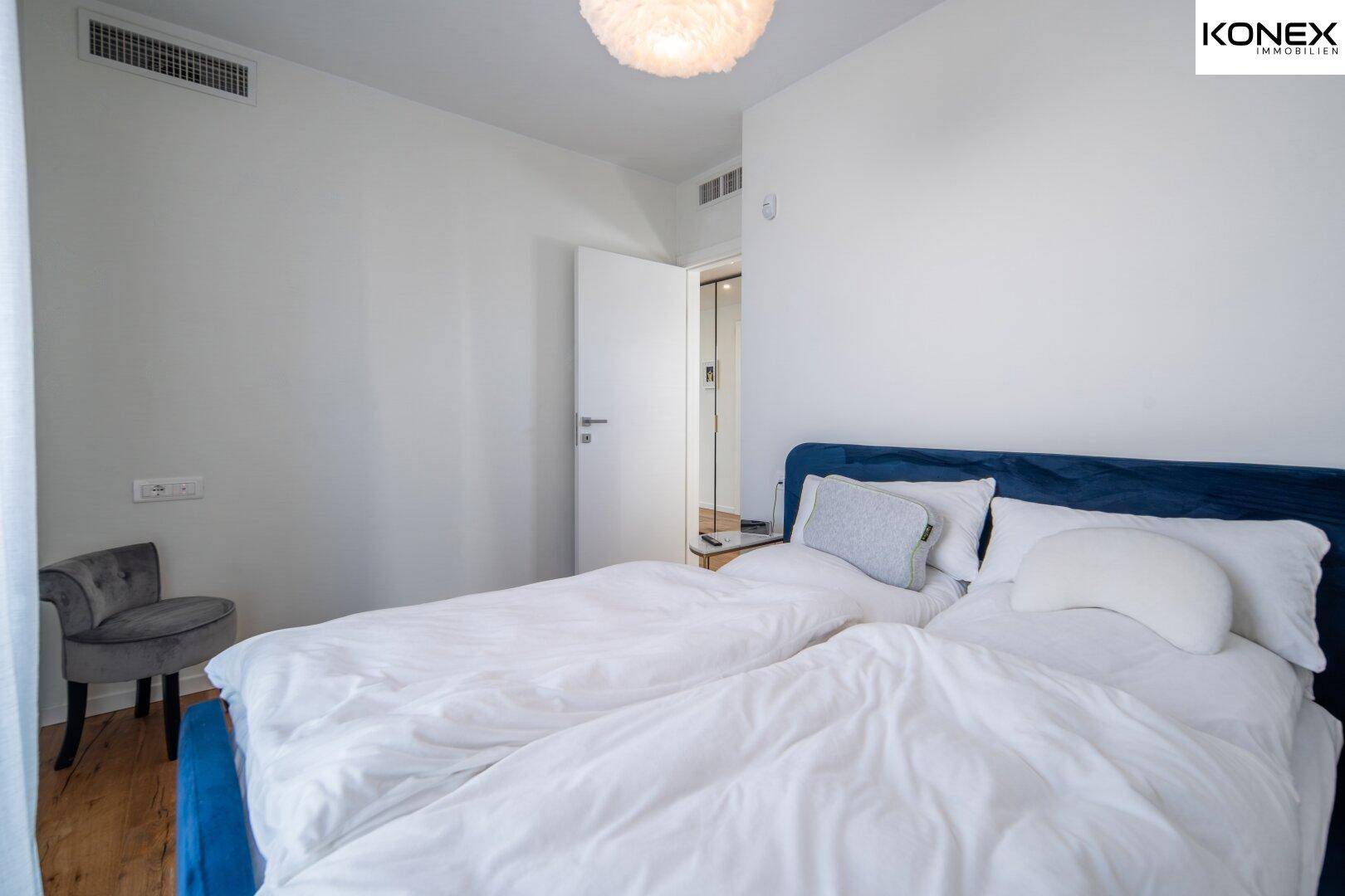 Helles Schlafzimmer mit Doppelbett, Holzboden und schlichter, moderner Einrichtung.