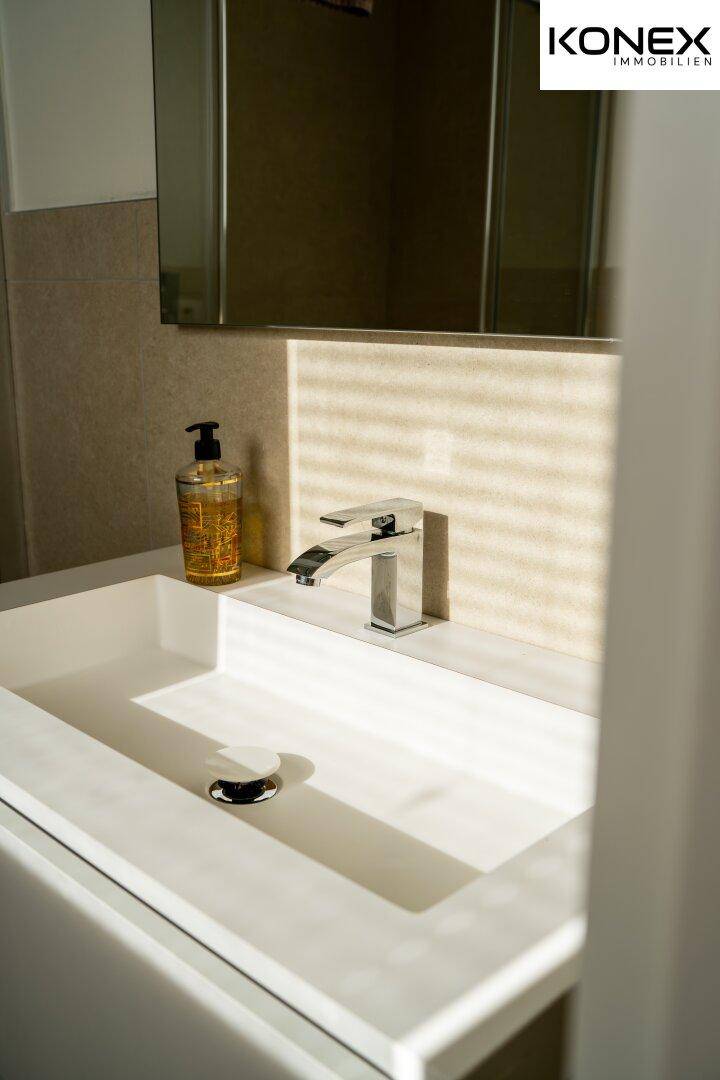 Modernes Einzelwaschbecken mit stilvollem Wasserhahn und Spiegel im Badezimmer.