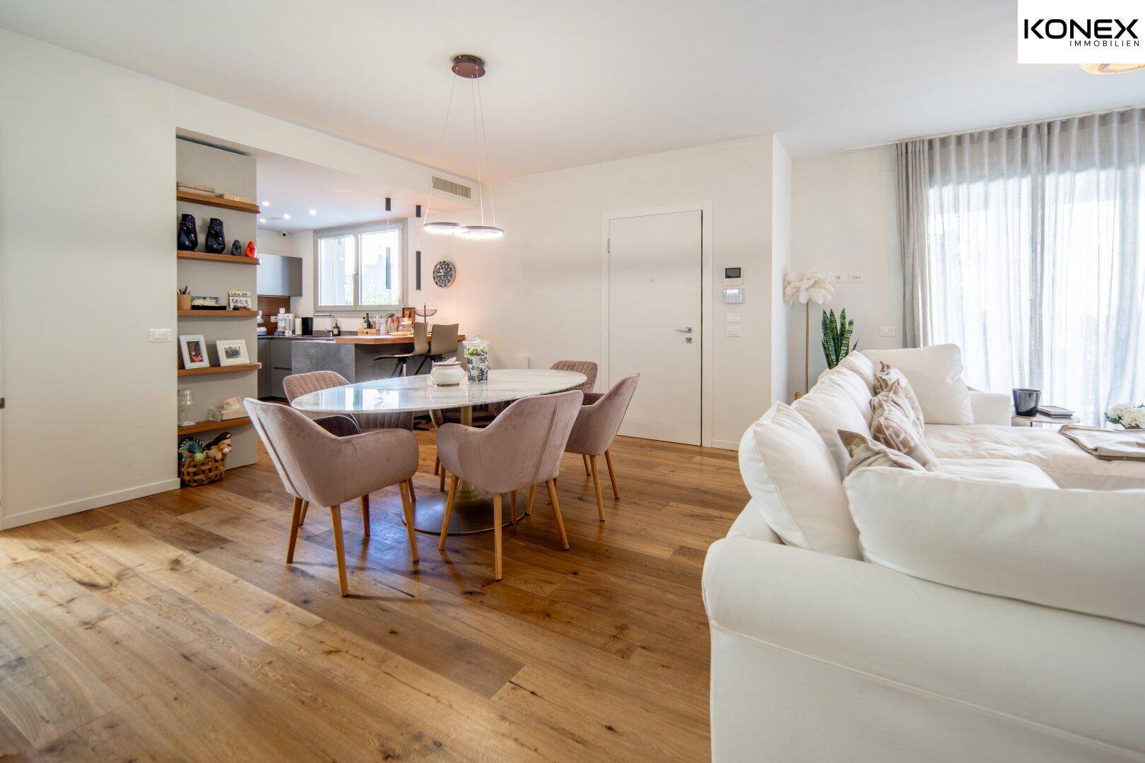Offener Wohn- und Essbereich mit Holzboden, elegantem Esstisch und großem Sofa, lichtdurchflutet.