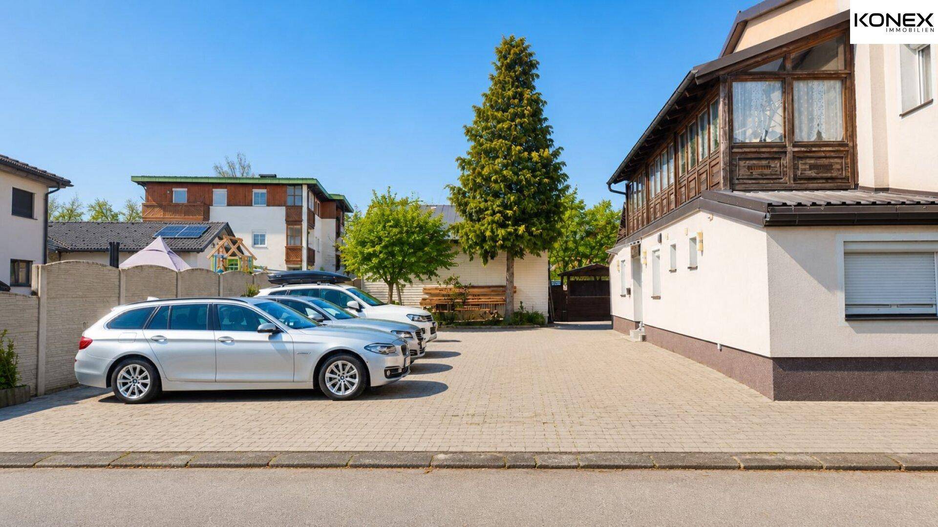 Geräumiger gepflasterter Parkplatz neben dem Gebäude mit mehreren geparkten Autos.