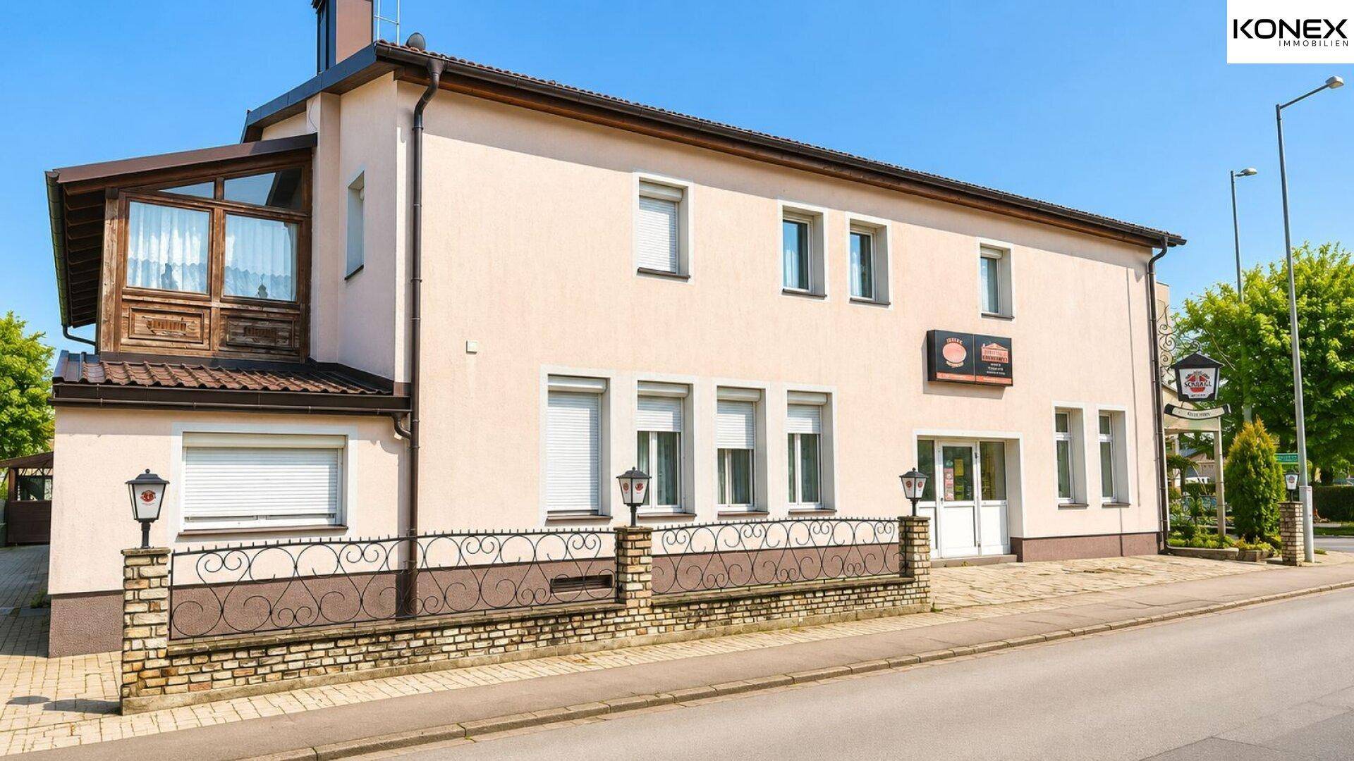 Rückansicht des Gebäudes mit einem verglasten Anbau und traditionellen Fensterläden.