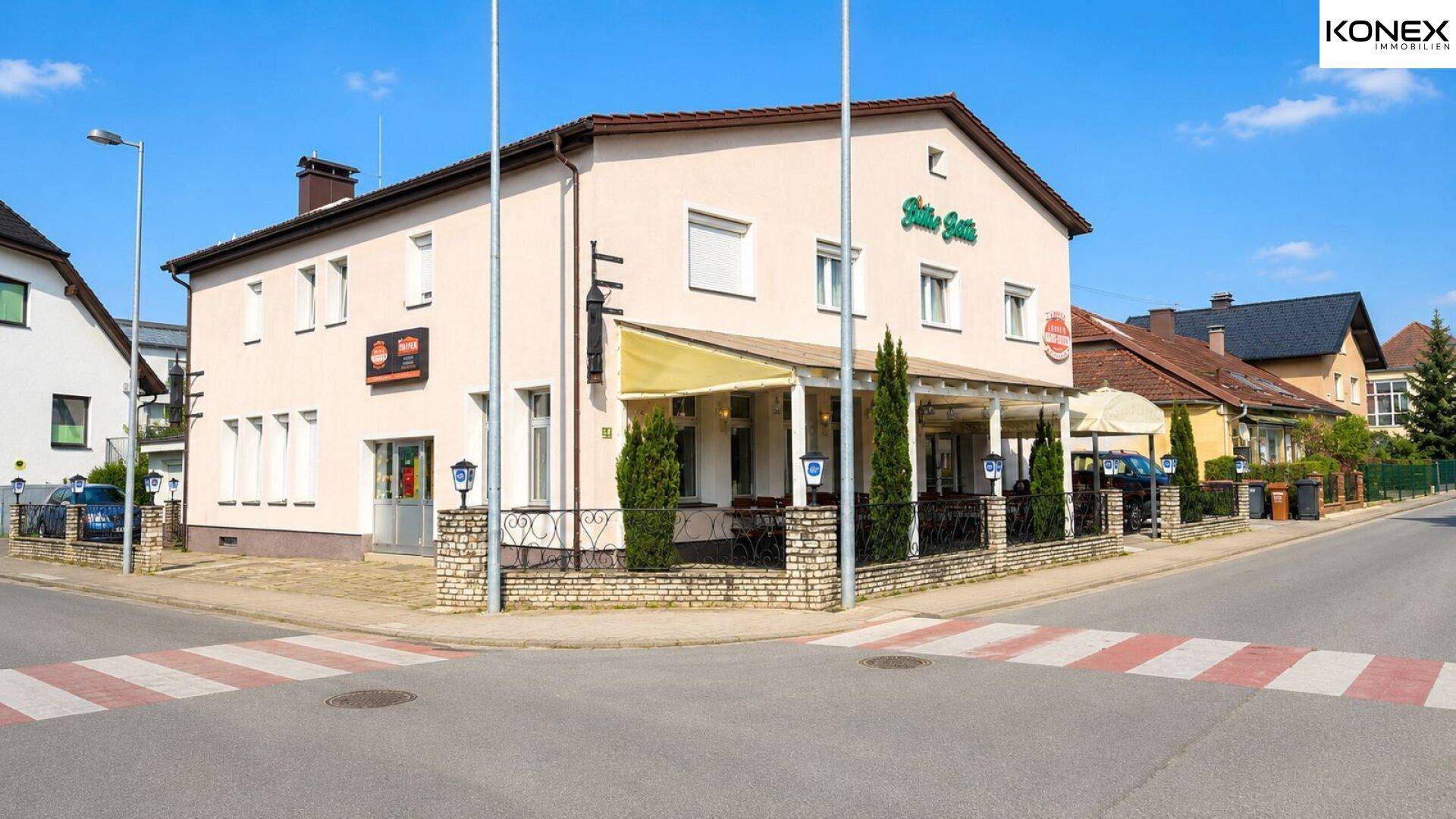 Das Gebäude präsentiert sich mit einer einladenden Außenterrasse und Blick auf die Straße.