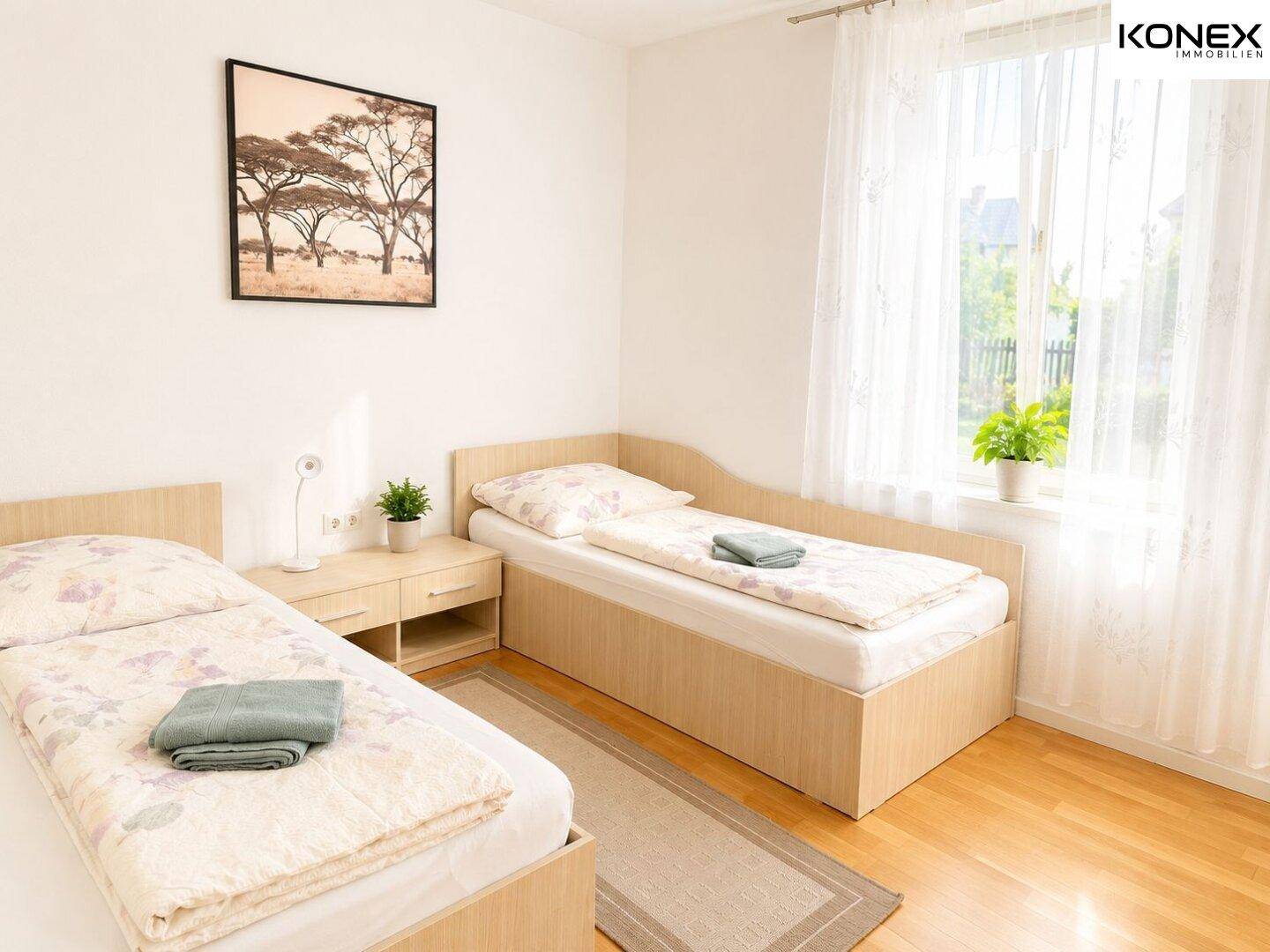 Helles Schlafzimmer mit zwei Einzelbetten, Holzboden und einem großen Fenster mit Vorhängen.