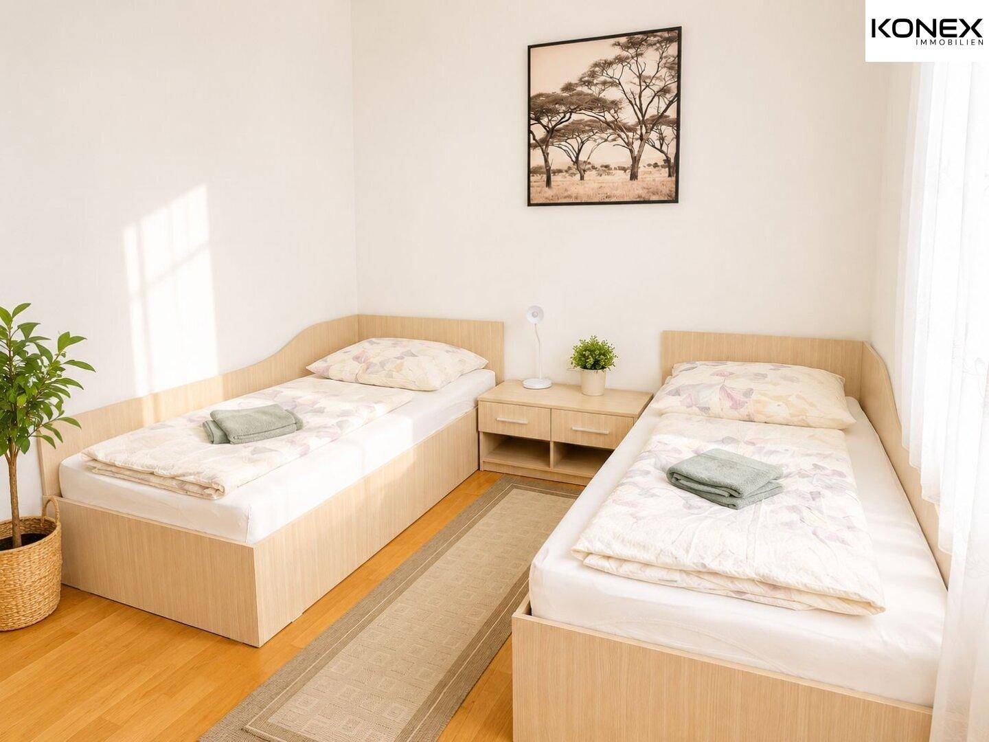 Gemütliches Schlafzimmer mit zwei Einzelbetten, Holzboden und einer Zimmerpflanze.