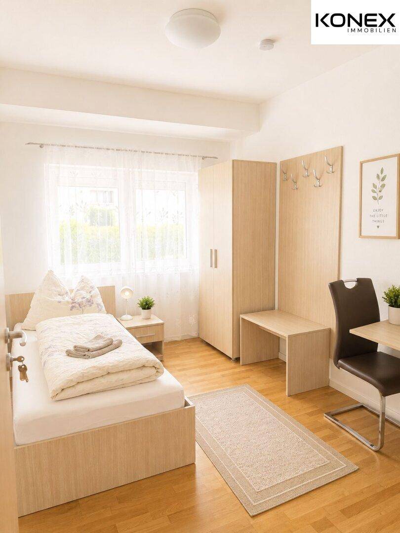 Einzelzimmer mit Bett, Schreibtisch, Kleiderschrank und hellem Holzboden.